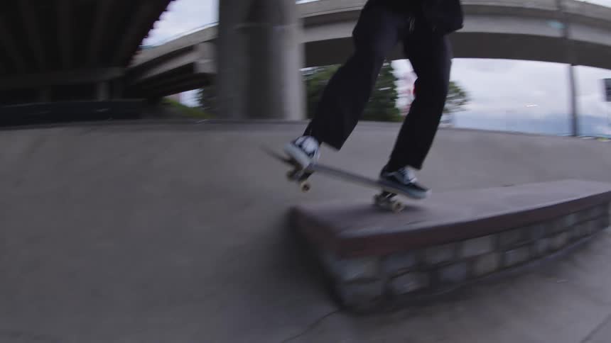 A young male adult performing skateboarding tricks at an outdoor ramp during daytime