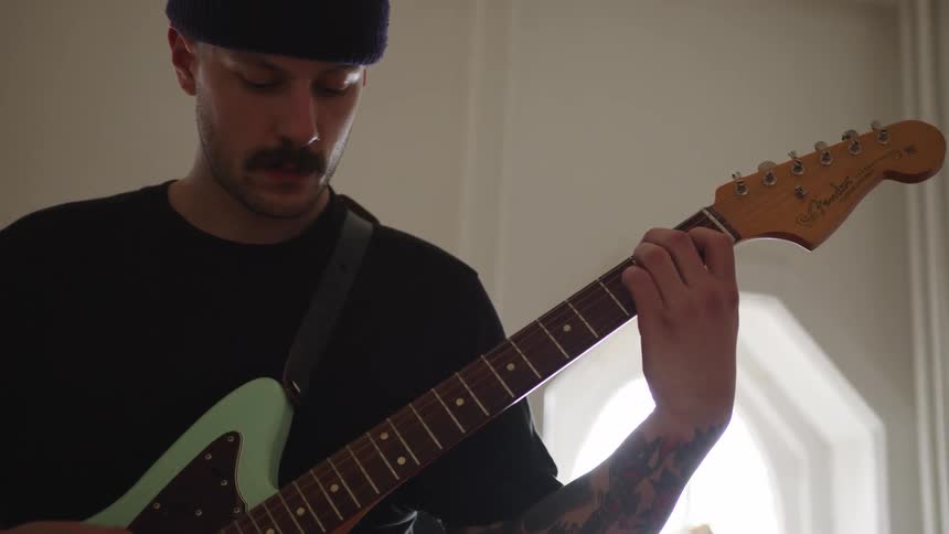 Musician plays an electric guitar near a window