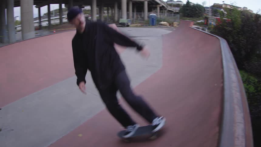 The man is riding his skateboard back and forward up the ramps