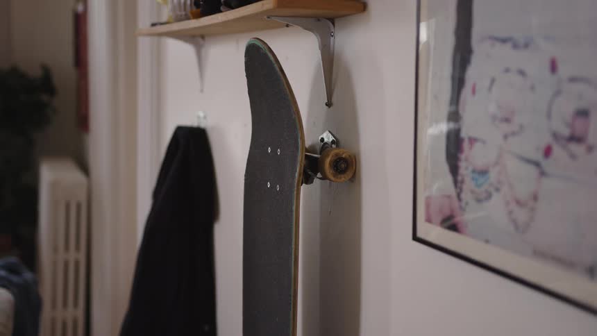 A wall with a skateboardcoatpainting and a shelf hanging