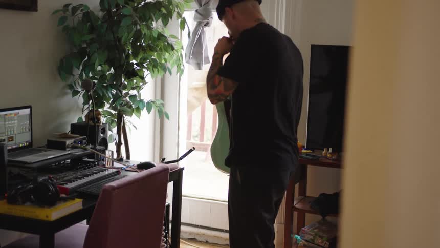 Male musician standing in his music studio puts down his electric guitar