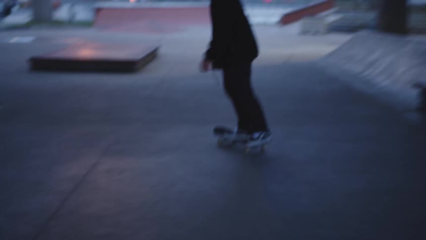 The man rides his skateboard in the skate park under the overpass