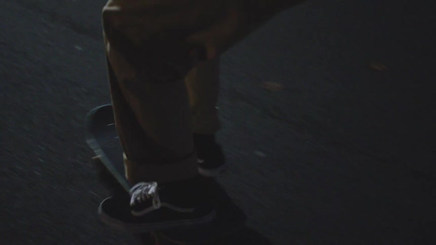 Sneakers in motion on skateboard over a dimly lit pavement