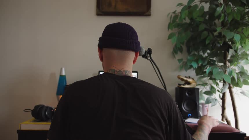Close up of a young man working with gadgets at a desk in a music studio during daytime