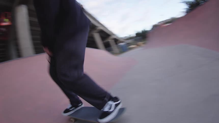 The man is skateboarding on ramps by the tall overpass