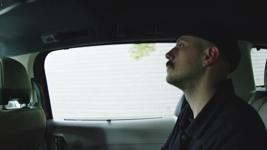 A man rides in the back of a car
