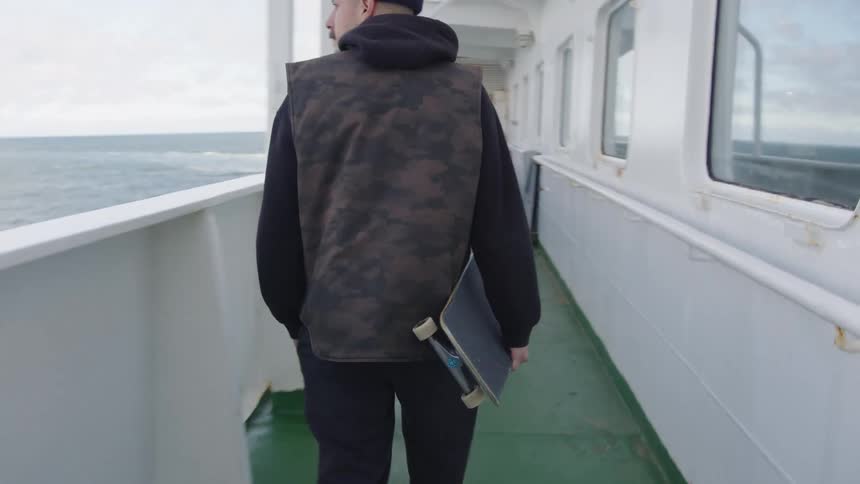 A man carries a skateboard on a boat