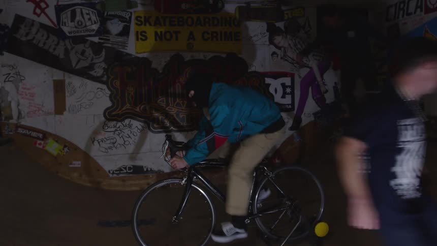 Teenagers skate on ramps around a person on a bicycle