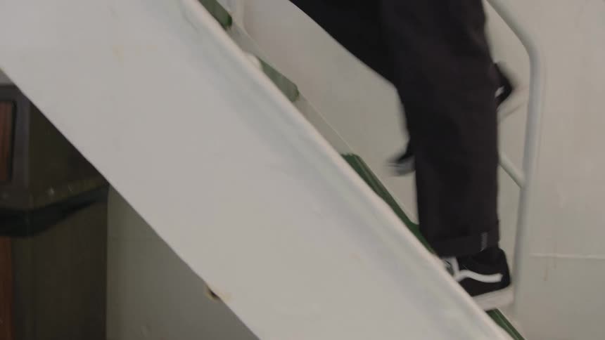 Person walks up a white staircase wearing black shoes
