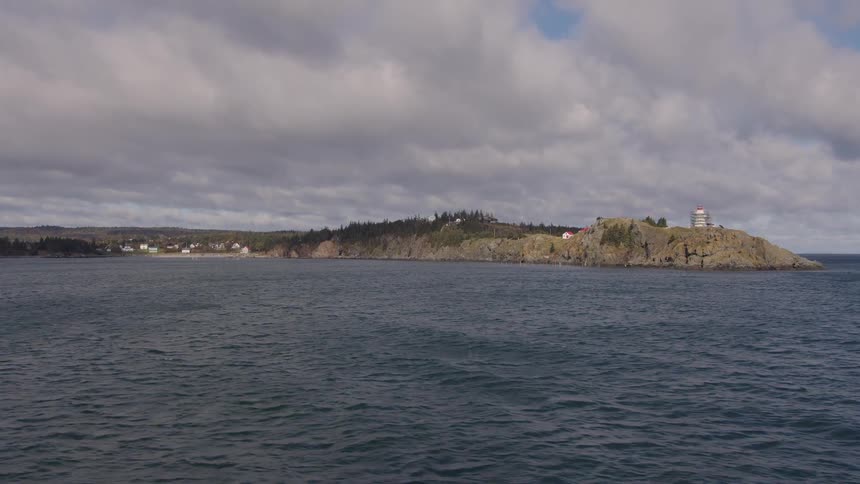 Rocky cliff by the ocean with a coastal town in the background