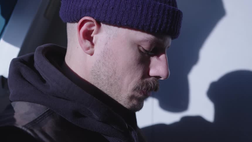 Man wearing a dark beanie in a side closeup partially lit by natural light