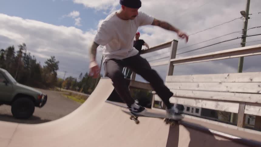 The man skates on the ramp by the woods