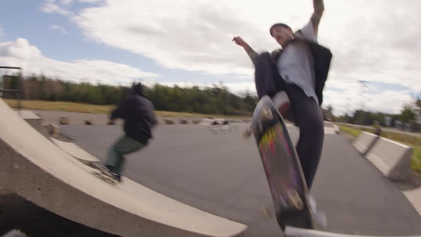 Two young male adults skateboarding at an outdoor skating ramp in a city during daytime