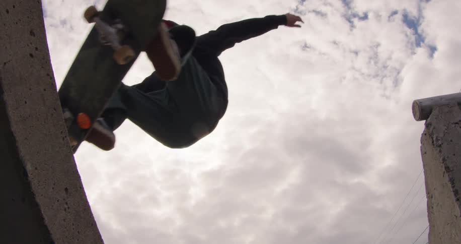 Skateboarder performs an aerial jump with a cloudy sky in the background