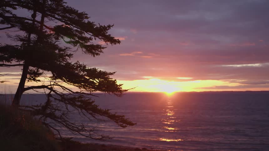 Sun setting on the horizon over the ocean as the tide gently rolls in
