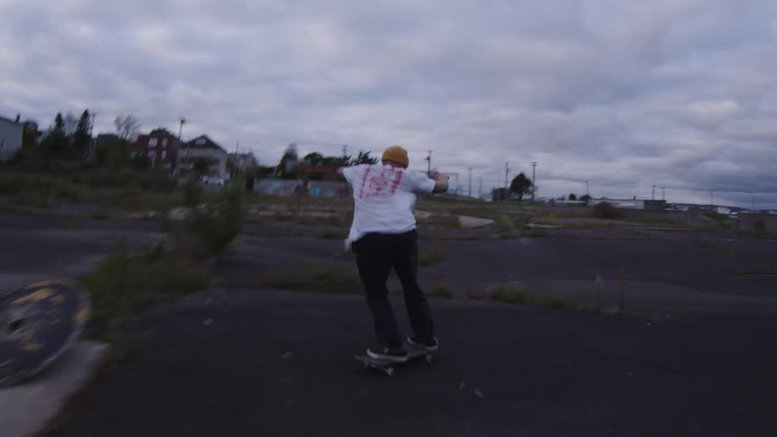 A guy skateboards in a vacant lot