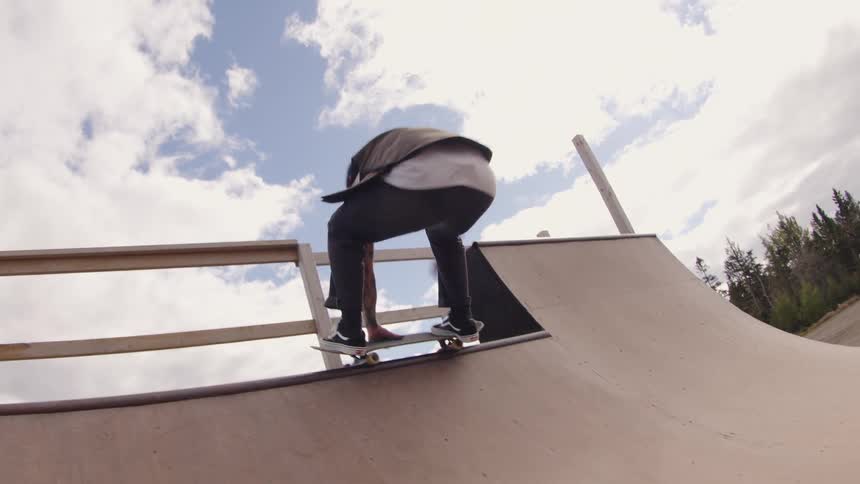 A young male adult skateboarding on an outdoor ramp in a city during daytime
