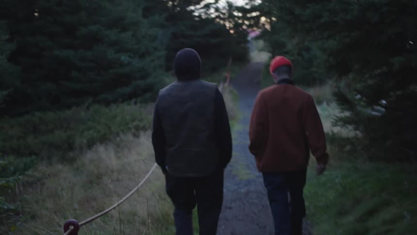 Two men walk along a trail through the woods on a winter day