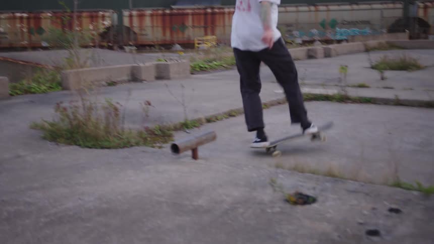 A young man rides a skateboard across an open concrete platform under the bright midday sun gliding smoothly in the clear expansive space