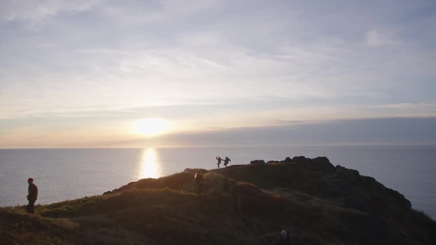 Two people are dancing by the cliff on the shore
