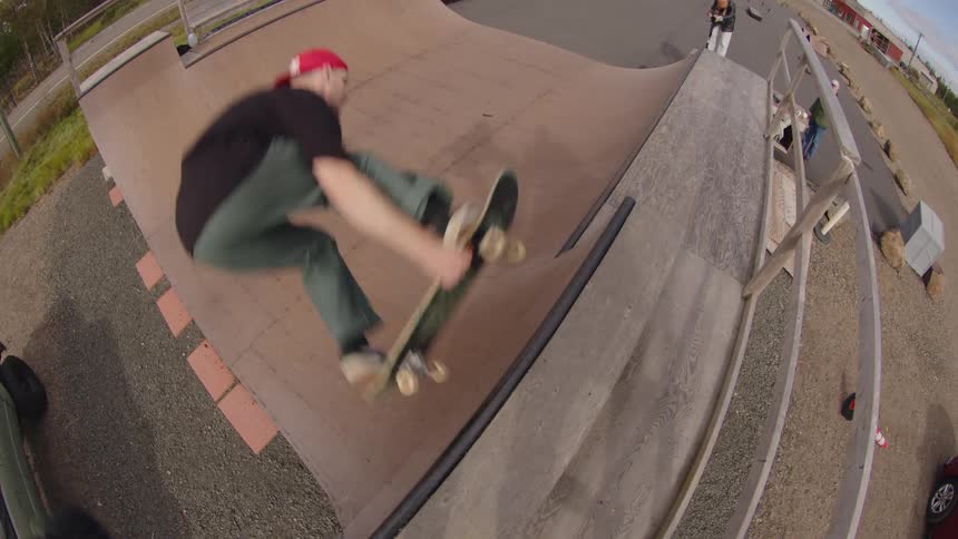 A young male adult skateboarding on an outdoor ramp in a city during daytime