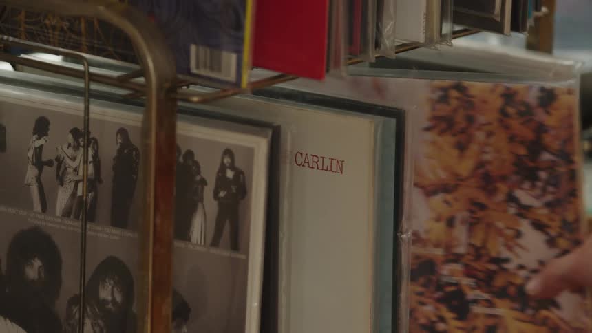 Hand flips through vinyl records in a shop