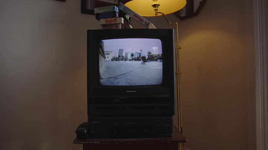 A television displays a skateboarding show with a lamp placed on top of it