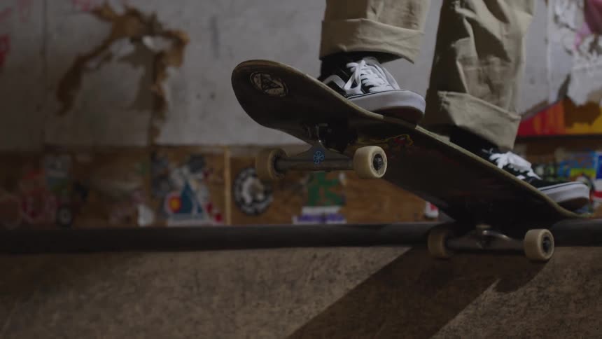 Skateboarder prepares to slide on the rail in an indoor skatepark with graffiticovered walls