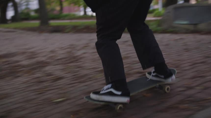 The man tries to balance while skateboarding on the brick walkway