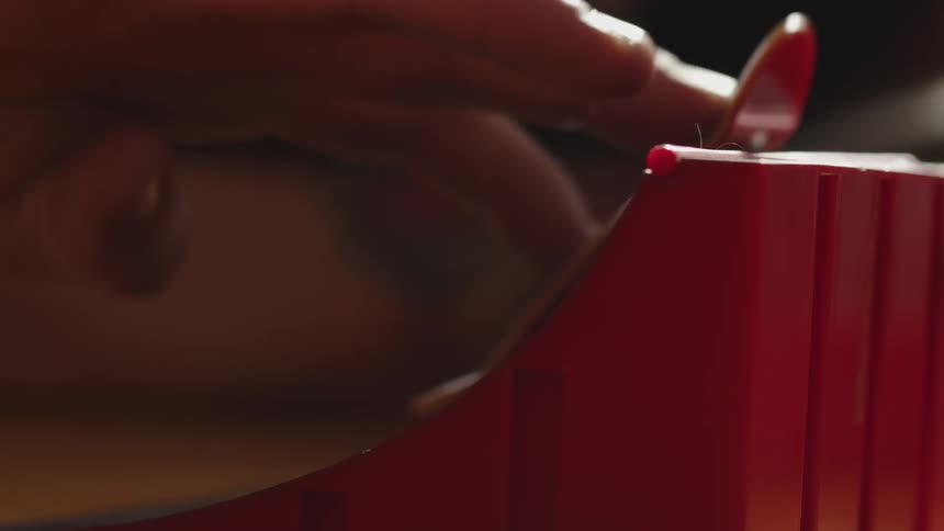 Hand maneuvering a fingerboard on a red ramp