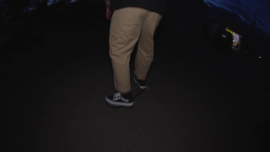 The man is hopping around on his skateboard at night