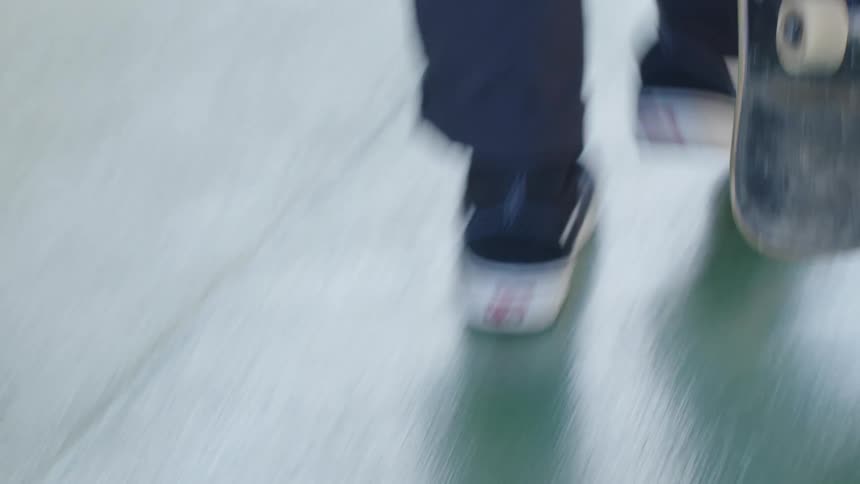 Person holding a skateboard while walking on a sunlit track
