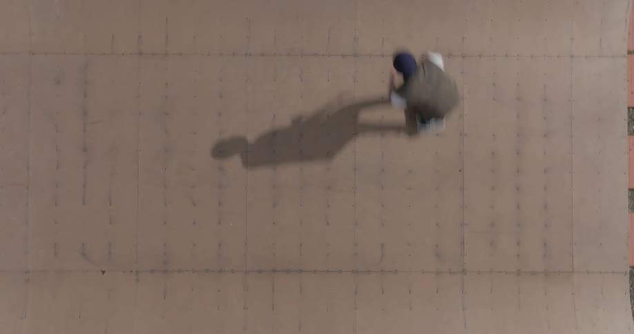 Skateboarder performing a trick on a ramp seen from above