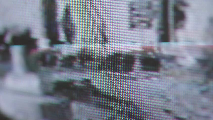 The video is an extreme closeup shot of a tv screen or monitor clearly showing the individual red green and blue pixels that form the imagethe visual content on the screen is abstract and highly distorted with bright flashes of color and