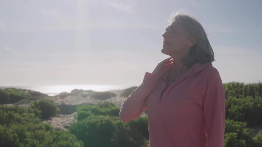 Woman in a pink top enjoying the sunny seaside landscape