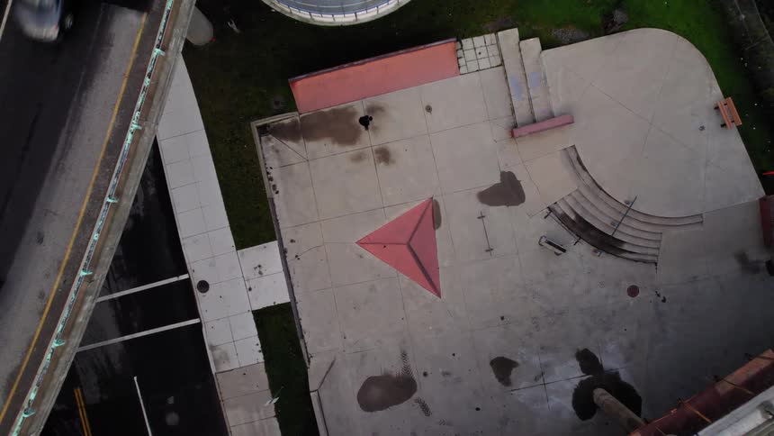 Person rides a skateboard in a concrete plaza seen from above