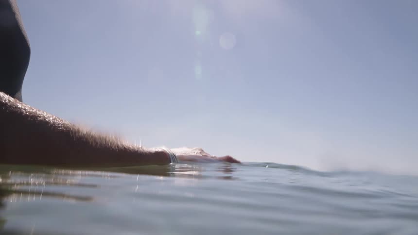 Woman in a swimsuit walks in the sea with her body partially submerged under bright sunlight
