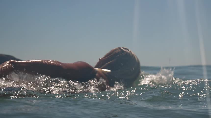 Woman swims through the water offshore on a sunny day