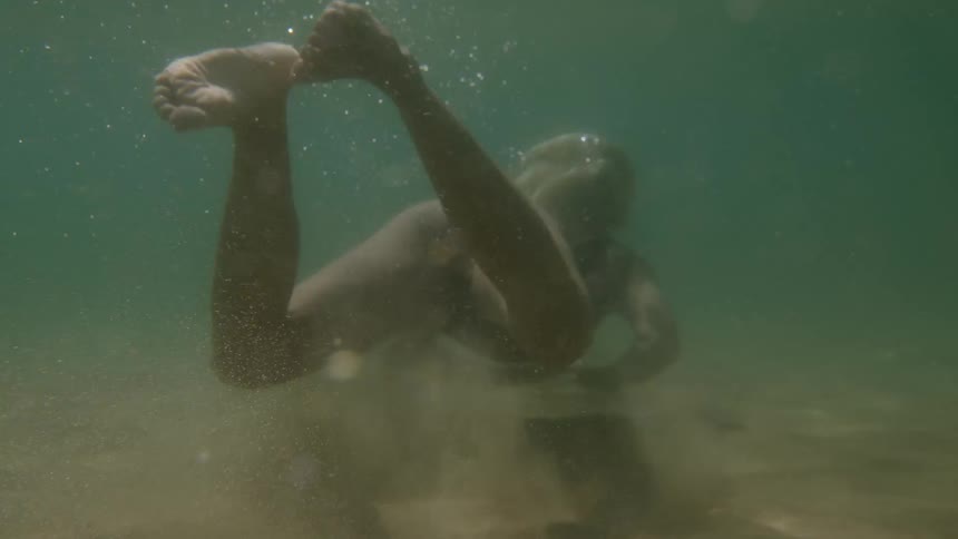 Swimmer glides underwater with sparkling bubbles