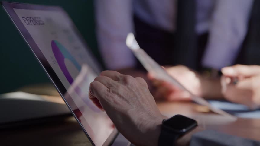 Person analyzing charts on a laptop during a business meeting