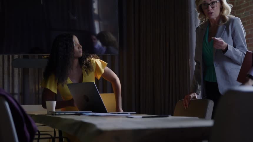 3 coworkers discuss work in a dimly lit meeting room