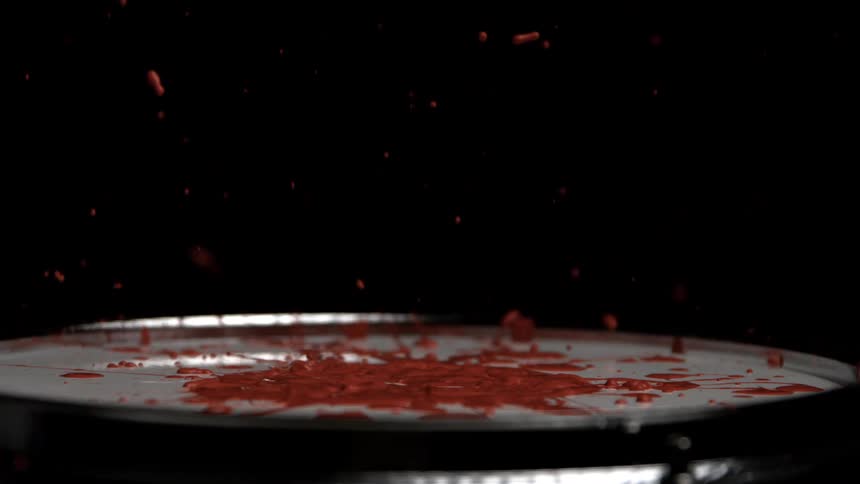 A drum stick hits a drum covered in paint which is ejected upwards