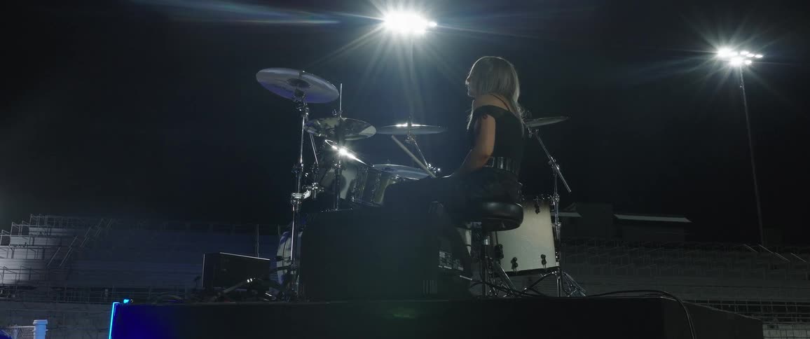 A female band artist practices on an empty stage playing her instrument during a rehearsal session