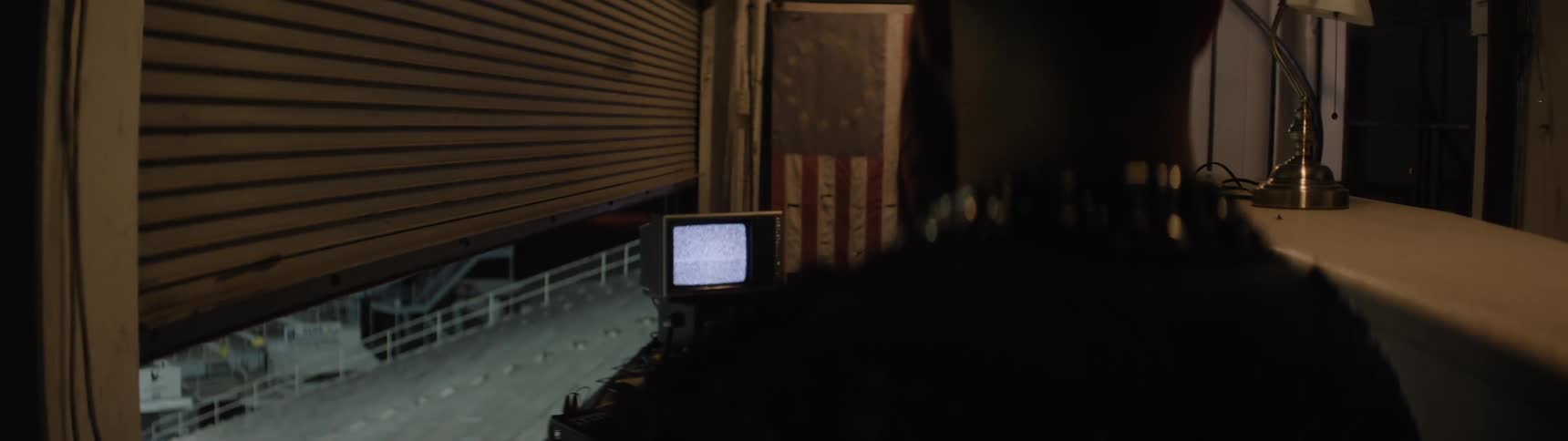 Person observes crt monitor in industrial setting with open metal door revealing outdoor staircase