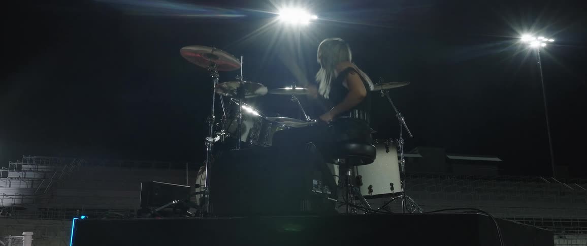 Drummer performs on an outdoor stage at night