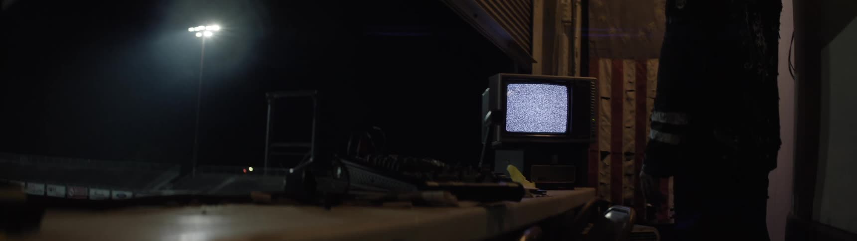 The man is standing in front of a small television in the booth
