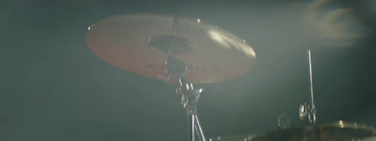 The woman is playing the drums and bobbing her head