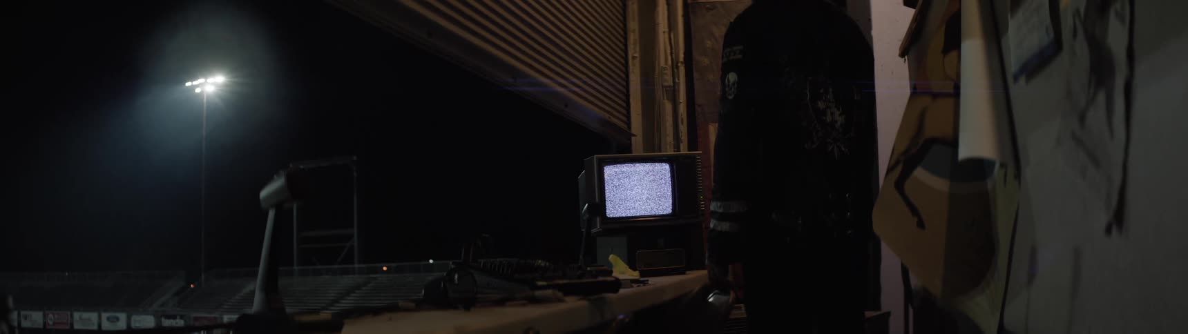 Person standing by door in dark room overlooking lit bleachers