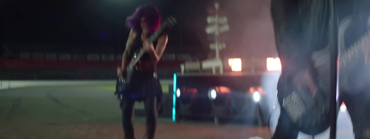 Guitarist jumping during a night performance in a lit stadium