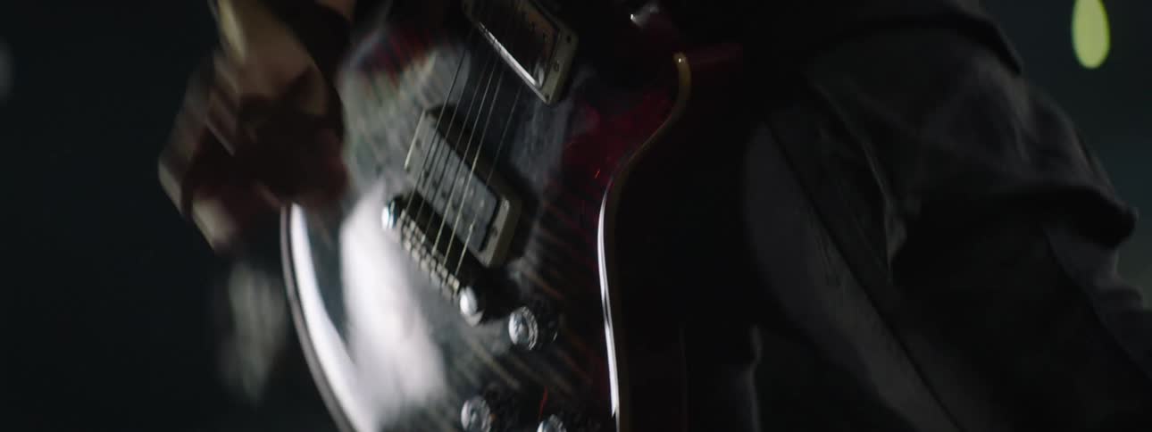 Musician plucking guitar strings in a dark setting